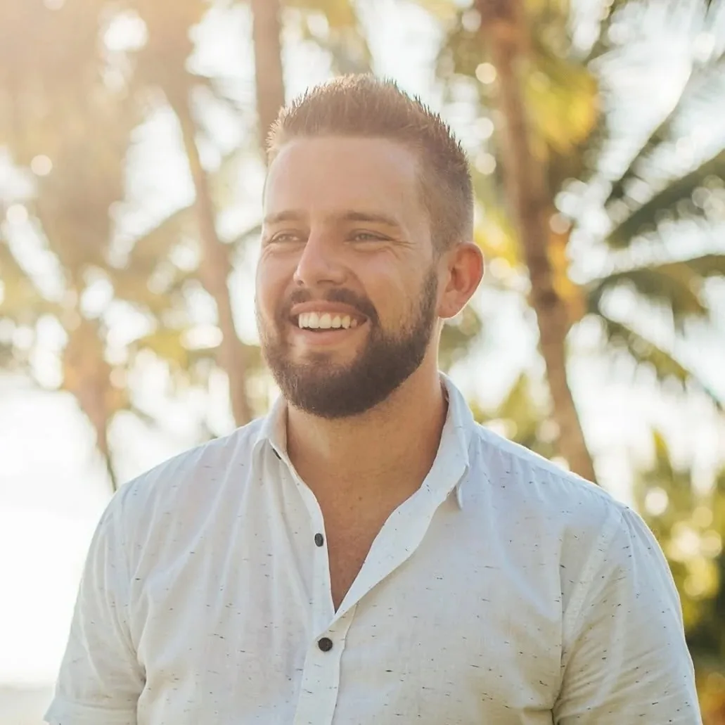 Luke smiling in golden light under palm trees